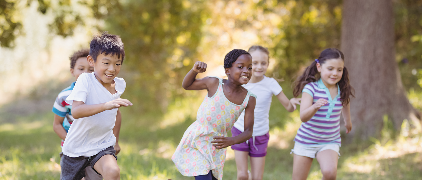 Kinder laufen verspielt über eine Wiese