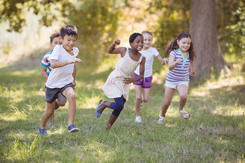 Kinder laufen verspielt über eine Wiese