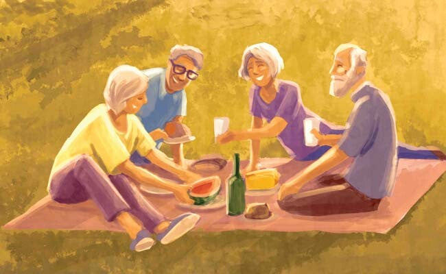 Zwei ältere Paare sitzen im Park und machen ein gemeinsames Picknick.