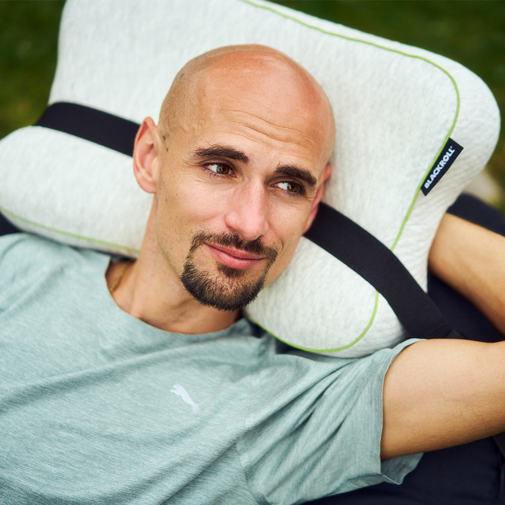 Person liegt im Freien auf dem Blackroll recovery Pillow