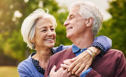 Paar umarmt sich lächelnd in der Natur, Blickkontakt, verschwommener Hintergrund.