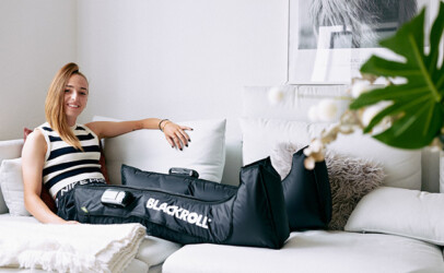 junge frau sitzt auf der couch und hat die blackroll Compression boots an, döbling einkaufstage 2025