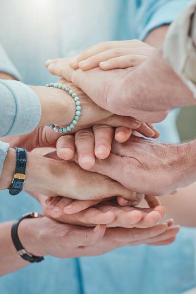 Mehrere übereinandergelegte Hände.