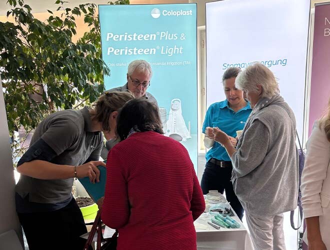 Vier Frauen und ein Mann im Gespräch beim Stoma-Infotag – Produktvorführung und Beratung rund um Stomaversorgung.