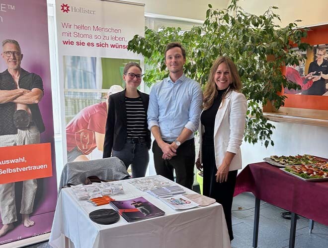 Drei Vertreter:innen der Firma Hollister am Infotisch mit Stomaprodukten und Werbematerialien beim Stoma-Infotag.