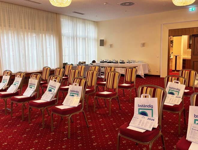 Seminarraum beim ISK-Seminar vor Beginn: aufgestellte Stühle mit Begrüßungstaschen, bereit für die Teilnehmenden