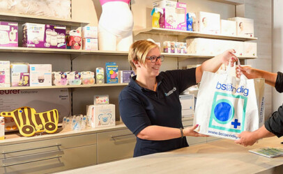 bständig Mitarbeiterin übergibt einem Kunden eine bständig Einkaufstasche im Geschäft.