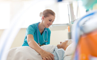 Krankenschwester unterstützt eine ältere Dame im Bett.