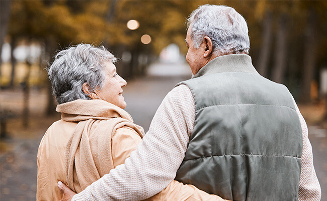 Paar spaziert umarmt in der Natur, Blickkontakt, verschwommener Hintergrund.