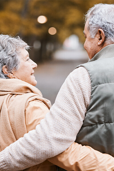 Paar spaziert umarmt in der Natur, Blickkontakt, verschwommener Hintergrund.