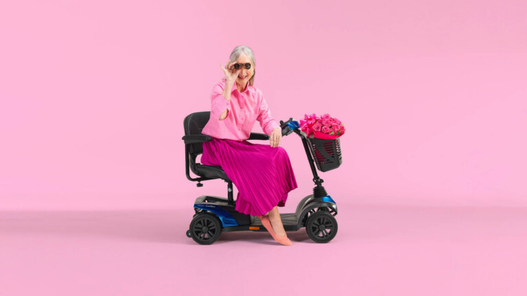 Elegant gekleidete Dame sitzt auf einem Mobilitäts-Scooter.