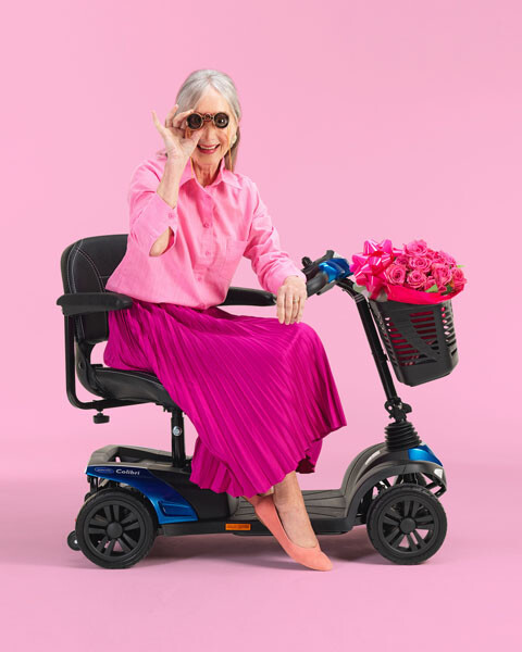 Elegant gekleidete Dame sitzt auf einem Mobilitäts-Scooter.