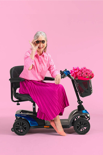 Elegant gekleidete Dame sitzt auf einem Mobilitäts-Scooter.