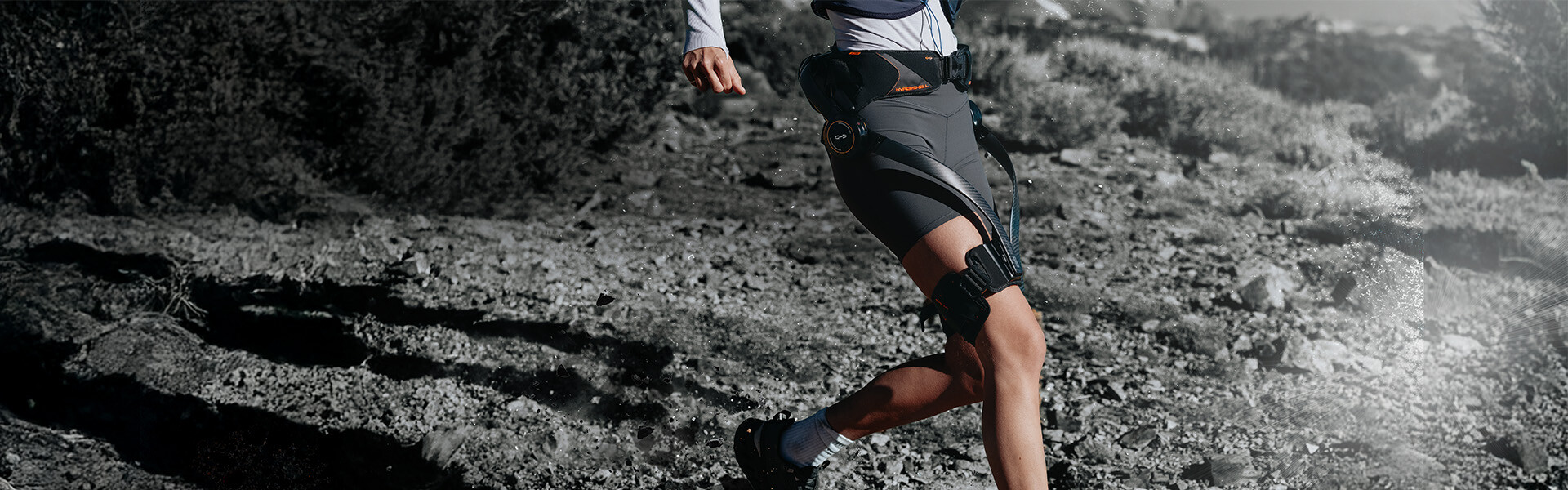 Sportliche junge Frau läuft Berg hinunter mit Unterstützung eines Hypershell Exoskeletts.