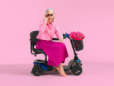 Elegant gekleidete Dame sitzt auf einem Mobilitäts-Scooter.