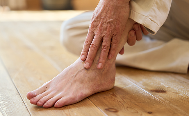 Ältere Person massiert eigenen Fuß.