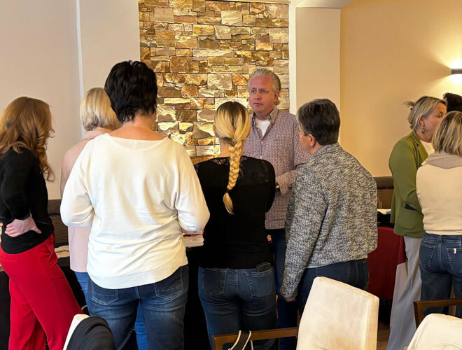 Firmenvertreter im Gespräch mit mehreren Teilnehmer:innen am Tisch mit Stoma-Materialien beim bständig Stoma-Seminar Krems 2026