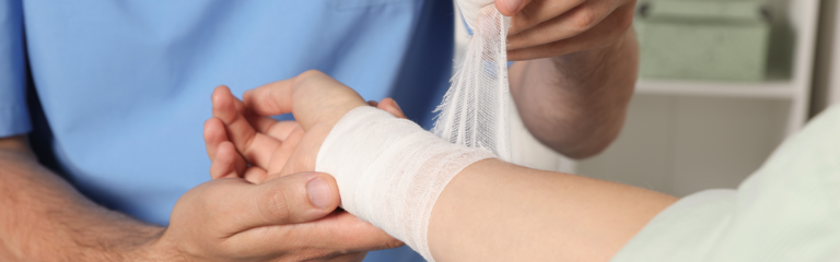 Medizinisches Fachpersonal verbindet das Handgelenk eines Patienten mit einer Bandage