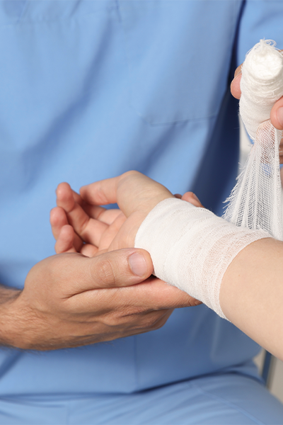 Medizinisches Fachpersonal verbindet das Handgelenk eines Patienten mit einer Bandage