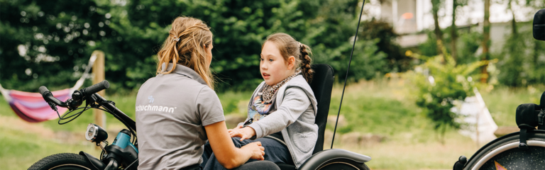 Therapeutin berät ein Kind in einem spezialisierten Therapierad im Freien