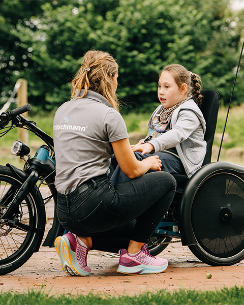 Therapeutin berät ein Kind in einem spezialisierten Therapierad im Freien