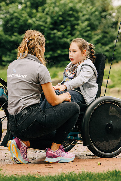 Therapeutin berät ein Kind in einem spezialisierten Therapierad im Freien