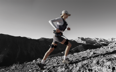 Sportliche junge Frau läuft Berg hinauf mit Unterstützung eines Hypershell Exoskeletts.