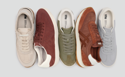 Sammlung von fitflop Schuhen in Grau, Grün und Beige Tönen. Der kleine Haufen Sneaker liegt auf grauem Hintergrund.